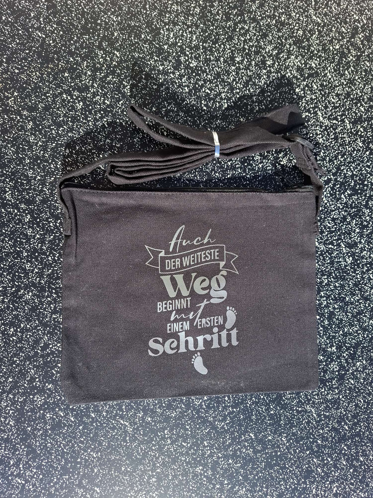 Schwarze Umhängetasche aus Baumwolle mit Spruch Auch der weiteste Weg beginnt mit einem ersten Schritt
